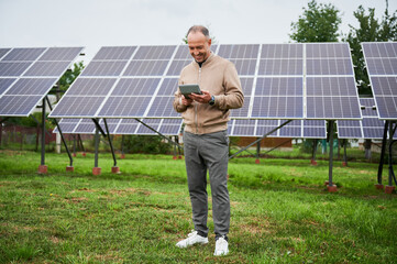 Young investor calculating his future profit from investments in green energy. Alternative energy resources and life improvement. Male with calculator on background solar panel.