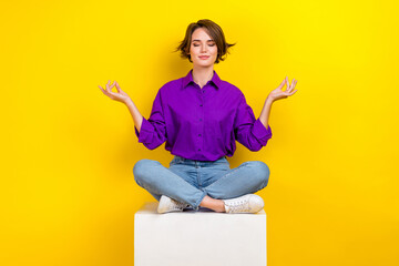 Wall Mural - Full size portrait of calm pretty girl sit podium cube closed eyes meditate isolated on yellow color background