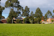 house in the parkVacant green grassy sports ground in a public local park in an Australian suburban neighbourhood.  Background texture of grass lawn with some residential houses in the distance. 