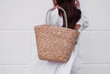 Straw stylish summer beach bag wicker basket on the background of a white wall. Women's fashion bag natural materials. Minimalist, eco-friendly bag, zero waste, mockup, copy space. Summer collections