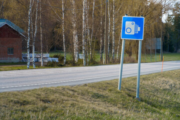 Blue speed camera traffic sign in countryside.