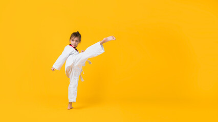 Banner: Asian-Australian girl poses in martial arts Practice taekwondo, karate, judo against a yellow background in the studio. Asian kids karate or Taekwondo martial arts. Sport kid training action.