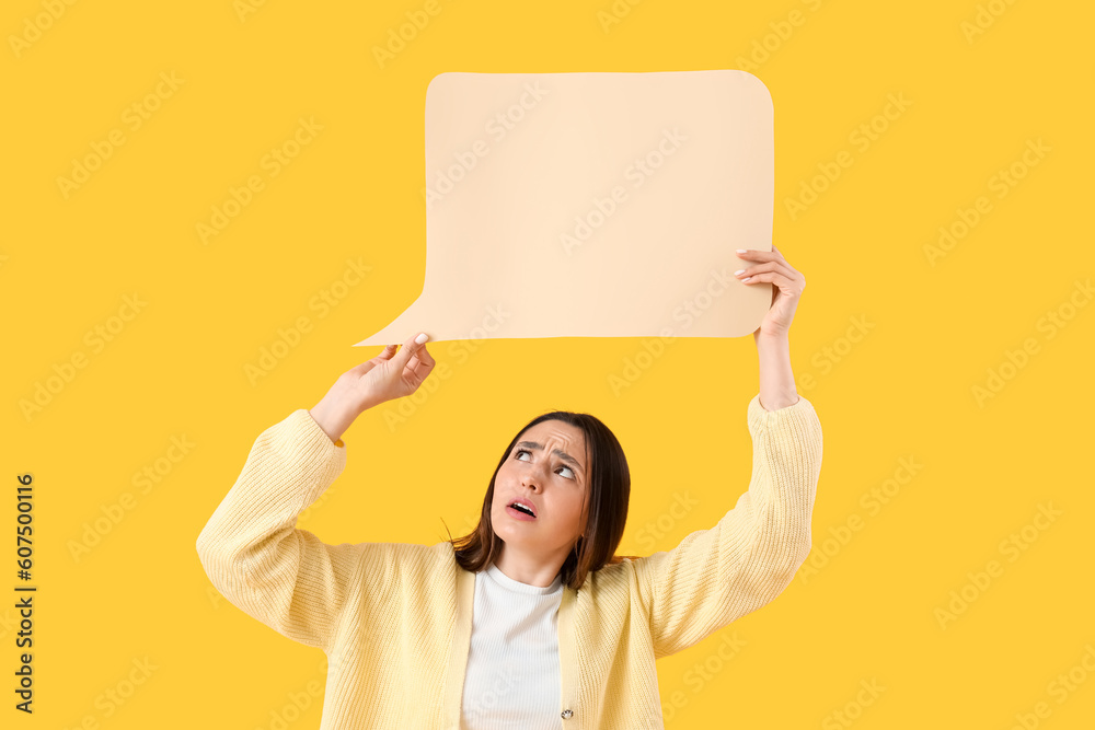 Upset young woman with blank speech bubble on yellow background
