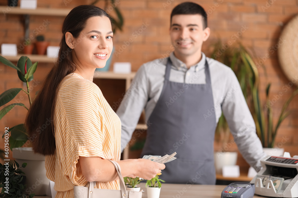 Young woman with dollar banknotes in flower shop