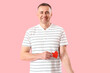 Mature blood donor with applied medical patches and paper heart on pink background