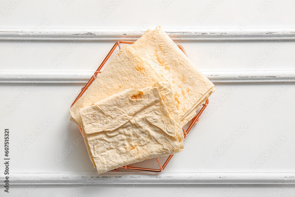 Grid with fresh lavash on white wooden background