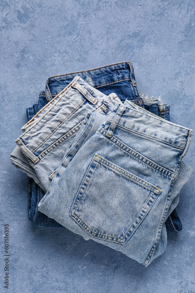 Different folded denim jeans on grunge blue background