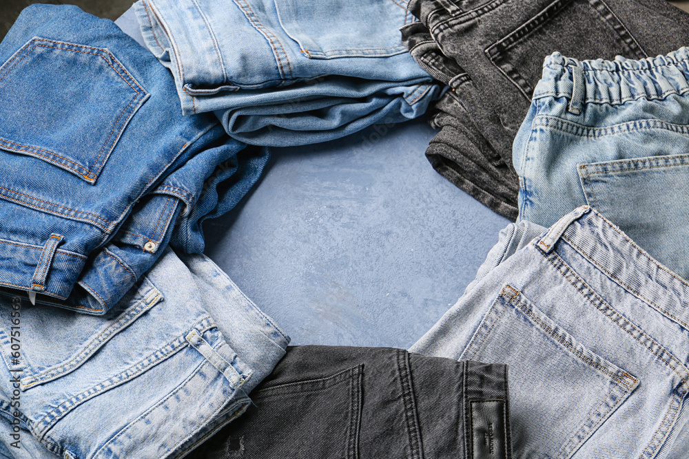 Frame made of different stylish denim jeans on grunge blue background