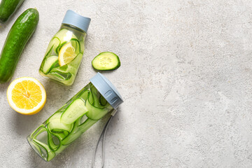 Wall Mural - Sports bottles of infused water with cucumber slices on grey background