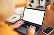 © baranq - Mock-up of adult woman using laptop with visible blank screen in living room at a table