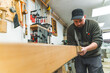 © PoppyPix - Caucasian carpenter using a tenon saw and cutting wood in his workshop, medium shot. High quality photo