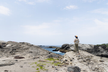 Poster - Woman stand on the rock and view the beach