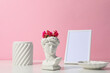 Decor concept with ancient head on white table against pink background
