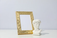 Blank Photo Frame And Ancient Head On White Table