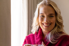 Closeup Portrait Of Smiling Beautiful Caucasian Young Woman Dressed In Red Bathrobe At Home