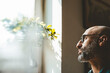 © Westend61 - Mature man wearing eyeglasses looking out of window at home