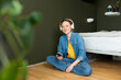 © Westend61 - Smiling woman listening music with headphones sitting on floor