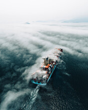 Aerial View Of A Cargo Ship Sailing The Hong Kong Bay With Low Clouds, China.