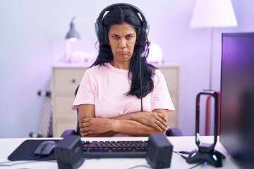 Poster - Mature hispanic woman playing video games at home skeptic and nervous, disapproving expression on face with crossed arms. negative person.