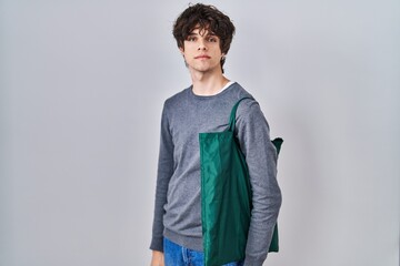 Canvas Print - Young man wearing reusable bag thinking attitude and sober expression looking self confident