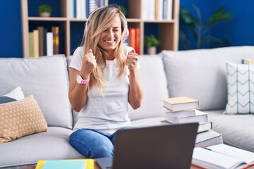 Poster - Young blonde woman studying using computer laptop at home excited for success with arms raised and eyes closed celebrating victory smiling. winner concept.