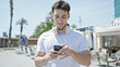 © Krakenimages.com - Young hispanic man using smartphone at coffee shop terrace