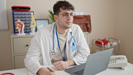 Poster - Young hispanic man doctor using laptop working at clinic