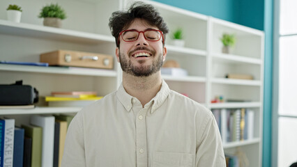 Wall Mural - Young hispanic man student smiling confident standing at library university