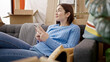 © Krakenimages.com - Young caucasian woman using smartphone sitting on sofa at new home