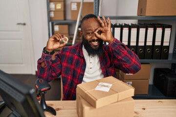 Poster - African american man working at small business ecommerce holding bitcoin smiling happy doing ok sign with hand on eye looking through fingers