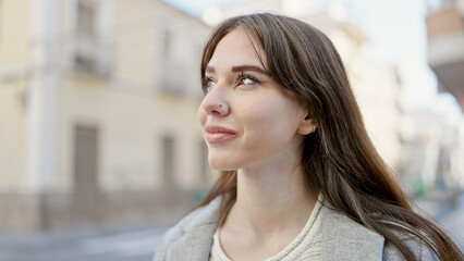 Poster - Young hispanic woman standing with serious expression looking to the side at street