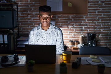 Wall Mural - Young hispanic man working at the office at night with a happy and cool smile on face. lucky person.