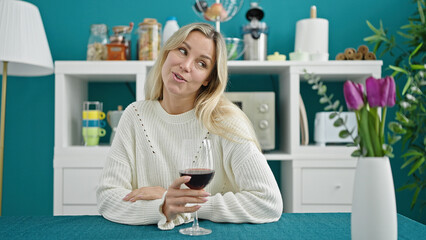 Sticker - Young blonde woman drinking glass of wine sitting on table speaking at dinning room