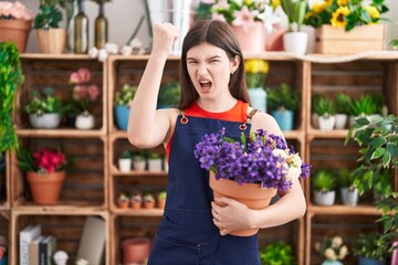 Sticker - Young caucasian woman working at florist shop holding pot with flowers annoyed and frustrated shouting with anger, yelling crazy with anger and hand raised