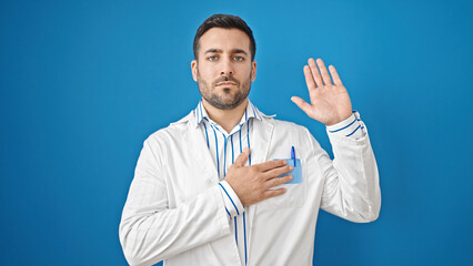 Poster - Young hispanic man doctor making an oath with hand on chest over isolated blue background