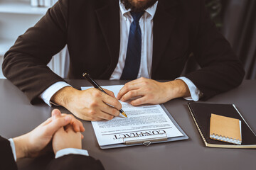 Closeup businessman sign contract or legal document with pen in his hand during corporate meeting for business deal or legal executive decision to pay off a loan or filing for bankruptcy. Equilibrium