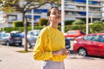 Young african american woman smiling confident listening to music at street