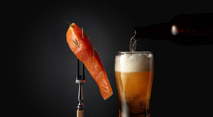 Poster - Smocked salmon with rosemary on a fork and a glass of beer on a dark background.