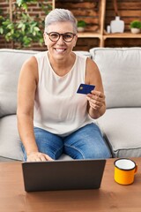 Sticker - Middle age woman using laptop and credit card at home