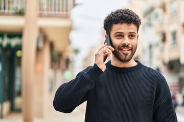 Sticker - Young arab man smiling confident talking on the smartphone at street