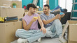 © Krakenimages.com - Two men couple drinking coffee sitting on floor speaking at new home