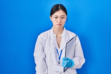 Poster - Chinese young woman working at scientist laboratory skeptic and nervous, frowning upset because of problem. negative person.