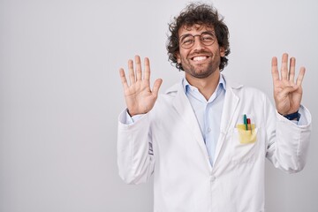 Canvas Print - Hispanic young man wearing doctor uniform showing and pointing up with fingers number nine while smiling confident and happy.