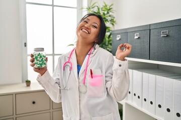 Wall Mural - Young asian doctor woman holding pills celebrating victory with happy smile and winner expression with raised hands