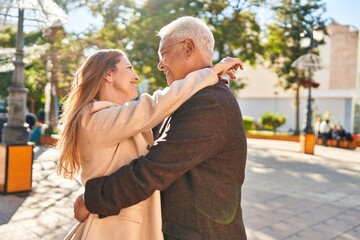 Sticker - Middle age man and woman couple hugging each other standing at park