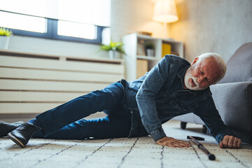 A Senior Man who is Using a Walking Stick is Lying on the Wooden Floor in his Apartment After he Fell in Serious Accident. Senior man lying on the floor of his room in an assisted living home