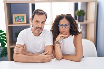 Canvas Print - Man and woman couple sitting on table with serious expression at home