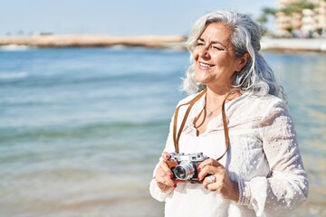 Wall Mural - Middle age woman smiling confident using professional camera at seaside