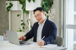 © Olha Tsiplyar - Happy asian businessman working, using laptop. Human resources. Finance concept. Multiracial