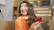 © Krakenimages.com - Young beautiful hispanic woman using smartphone sitting on sofa at new home